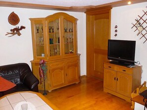 A living room with a wooden cabinet, a television on a wooden stand, and a leather sofa.