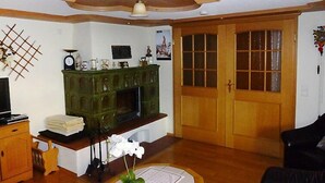 Un soggiorno con soffitto in legno, un mobiletto verde, un divano in pelle nera e una porta in legno con pannelli di vetro.