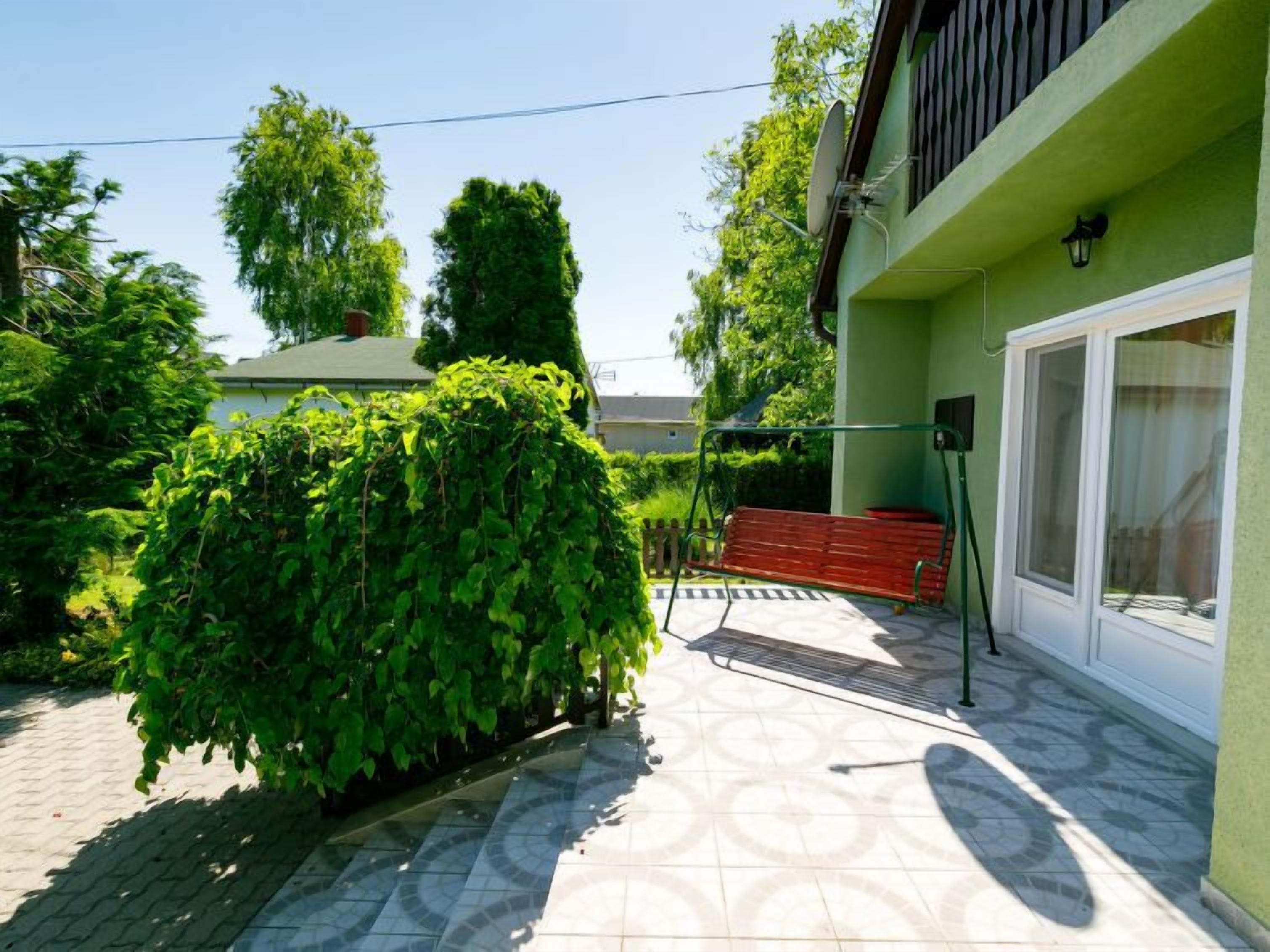 Een terras met een vloer van patroontegels, een groene wand en een rode bank.