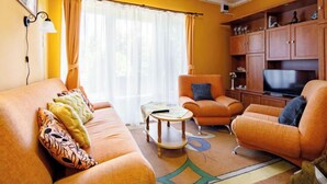 A living room with a sofa, armchairs, a coffee table, and a television.