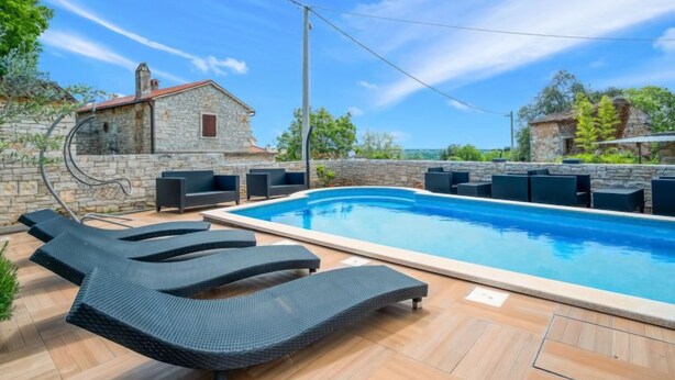 A swimming pool with lounge chairs and stone walls. - Apartment Ulika by Interhome (Poreč/Tar)