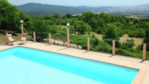 A swimming pool with lounge chairs and a view of mountains and greenery.