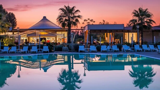 A poolside area with lounge chairs and a building with a covered patio. - Cecina Mare by Interhome (Cecina)