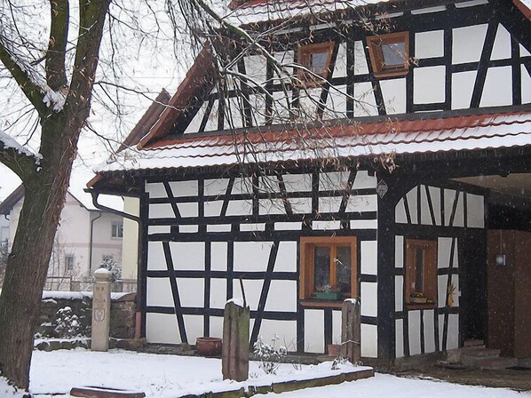 Une maison traditionnelle à colombages, avec un toit à forte pente, des poutres en bois et un remplissage en plâtre blanc.