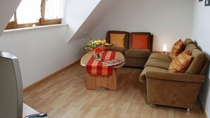 A cozy living room with a wooden floor, a sofa, a coffee table with a vase of flowers, and a television. - Dieboldshof by Interhome (Ichenheim)