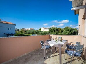 Eine Dachterrasse mit Tisch und Stühlen und Blick auf die Nachbarschaft, unter einem wolkenlosen Himmel.