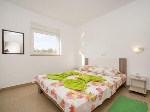 A bedroom with a bed, a window, a nightstand, and a wall-mounted light fixture. - Apartment B&B by Interhome (Medulin/Ližnjan)