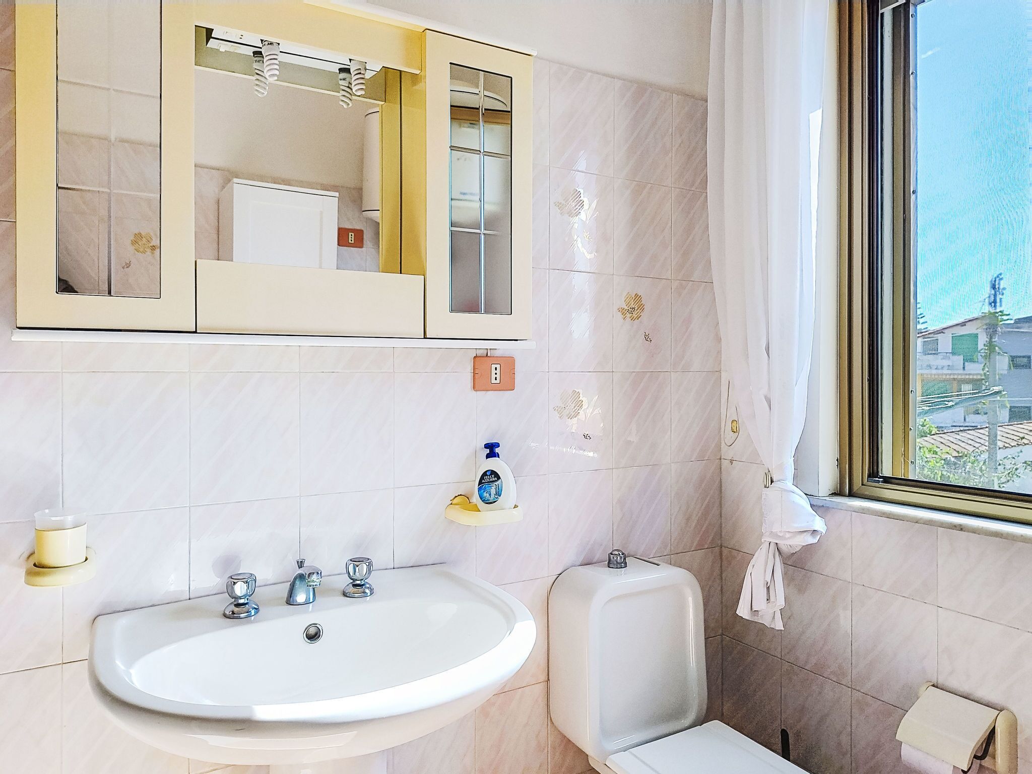 Ein Badezimmer mit Waschbecken, Spiegel und Fenster.