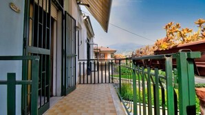 A covered outdoor corridor with a tiled floor, metal gates, and a view of a building and landscape. - Apartment Clara by Interhome (Mascali)