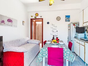 A cozy living room with a sofa and a dining table set for two. A kitchen with a refrigerator and microwave is visible to the right. - Apartment Clara by Interhome (Mascali)