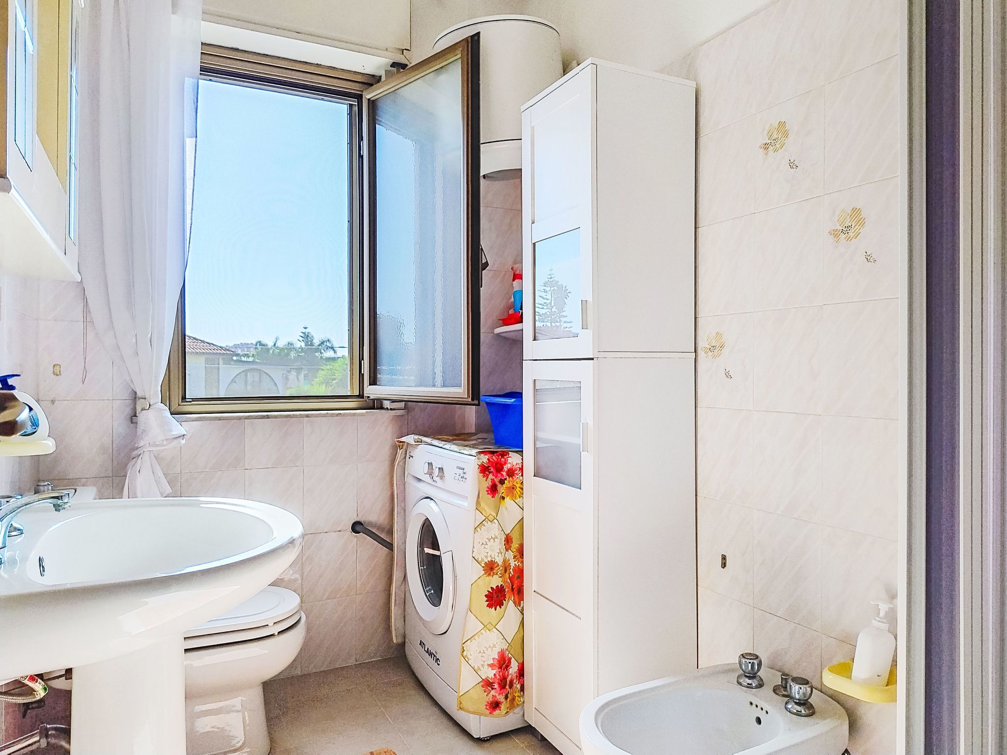 Ein kleines Badezimmer mit Toilette, Waschbecken und Waschmaschine.