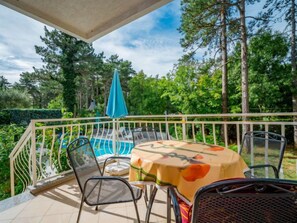 A balcony with a pool table, chairs, and a table with a floral tablecloth.