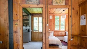 A wooden cabin interior with a kitchen, a bedroom with a bed and window, and a small bathroom. - Vacation home Dufaux by Interhome (Champex)