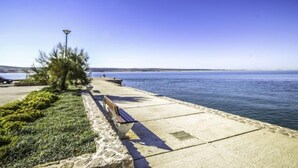 Un paseo marítimo con un banco, un farol y vistas al mar.