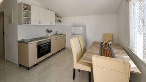 Una cocina moderna con comedor, que incluye un horno empotrado, un lavamanos y un refrigerador.