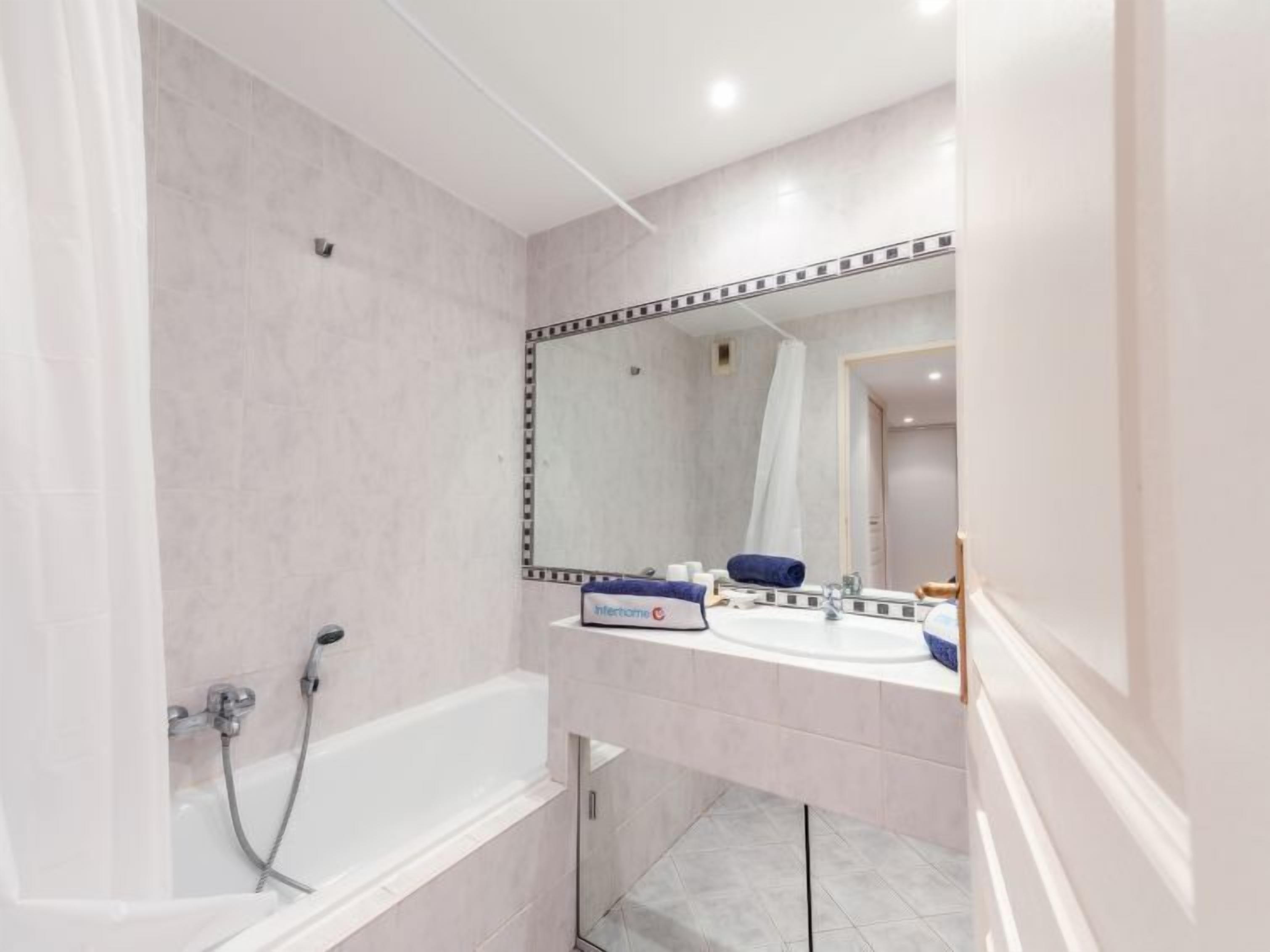 A modern bathroom with a bathtub, a sink, and a large mirror.