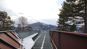Une passerelle métallique, bordée de neige, qui mène à une montagne.