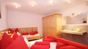 Une chambre à coucher avec un lit, des oreillers rouges, une armoire en bois et une salle de bain avec un lavabo et un miroir.