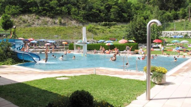 Un espace piscine doté de plusieurs toboggans et de parasols.