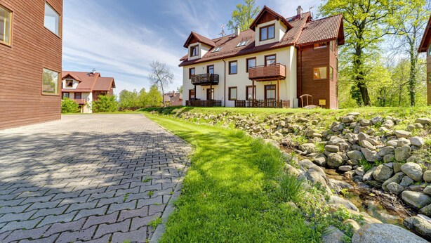 A large, two-story house with a paved driveway leading to a grassy area with a small stream. - Nad Łomniczką by Interhome (Karpacz)