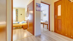 A hallway with wooden doors, a bed, a desk, and a chair in a room. - Nad Łomniczką by Interhome (Karpacz)