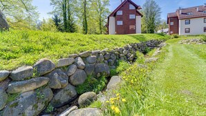 A stone wall leading to a modern house with a red roof, surrounded by lush greenery and trees. - Nad Łomniczką by Interhome (Karpacz)
