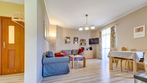 A spacious living room with a sofa, a dining table, and a kitchen area in the background. - Nad Łomniczką by Interhome (Karpacz)