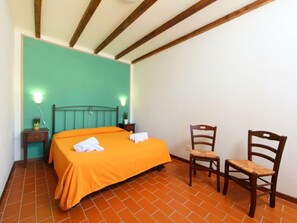 A room with a bed, two chairs, a nightstand, and a wall with a green accent.