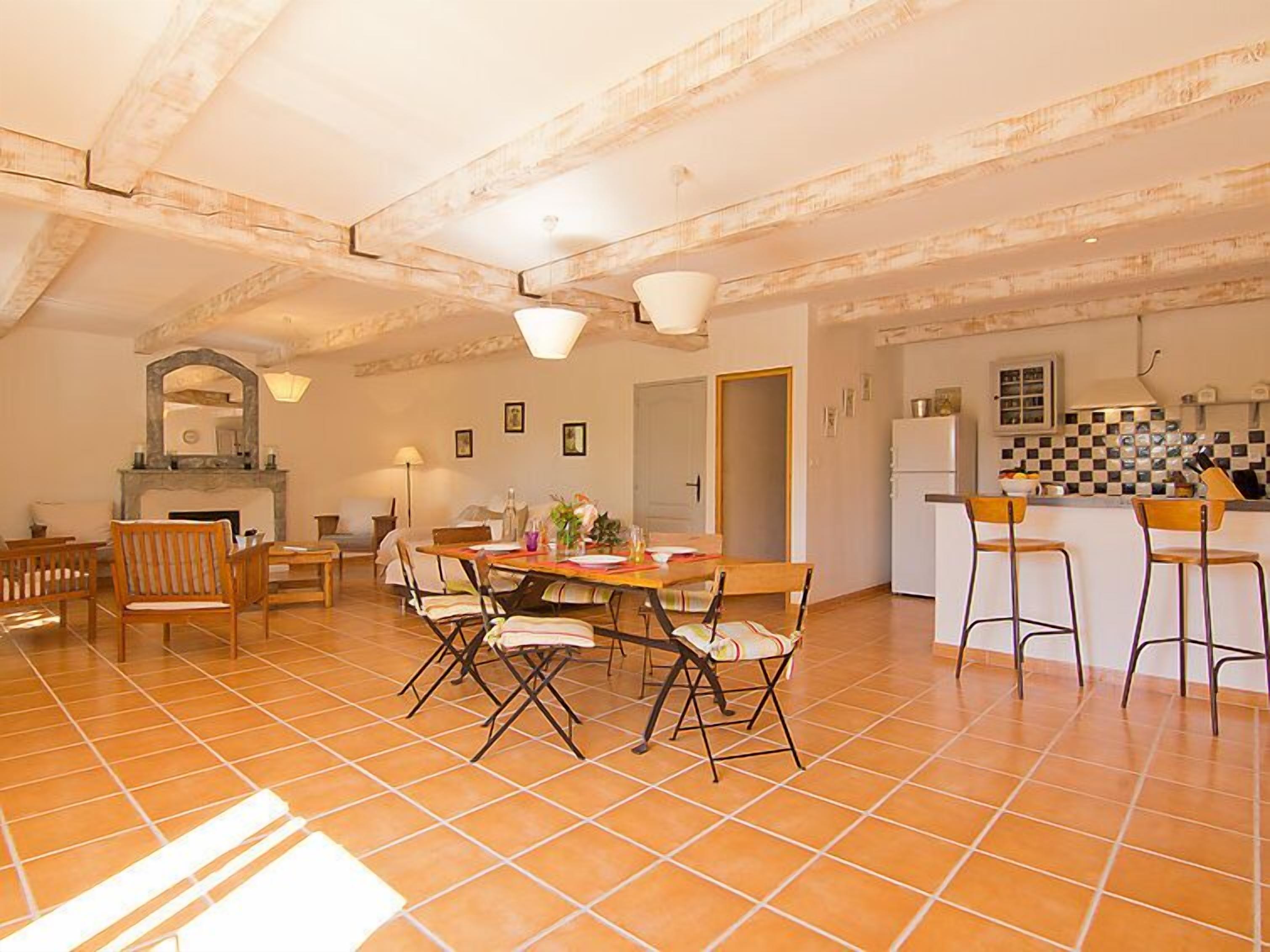 A spacious dining area with a large table and chairs, a fireplace, and a kitchen with bar stools.