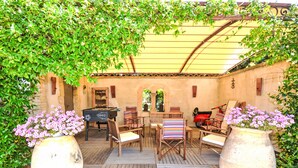 Eine Terrasse im Freien mit Holzmöbeln, einem Tischfußballspiel und Topfpflanzen.