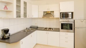 A modern kitchen with white cabinets, a gas stove, an oven, a microwave, and a coffee maker. - Plavac Mali by Interhome (Trstenik/Dingač)