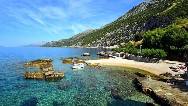 A coastal scene with clear waters, rocky outcrops, a sandy beach, and a mountainous backdrop. - Plavac Mali by Interhome (Trstenik/Dingač)
