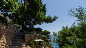 A stone staircase leading to a coastal area with a small table and a stone bench. - Plavac Mali by Interhome (Trstenik/Dingač)