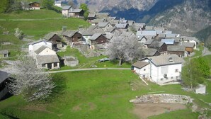 En landsby med traditionelle huse, en central hvid bygning og et bjerg i baggrunden.