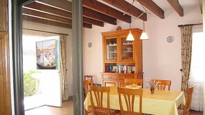 Un comedor con una mesa y sillas de madera, un armario con puertas de vidrio y un cuadro en la pared.