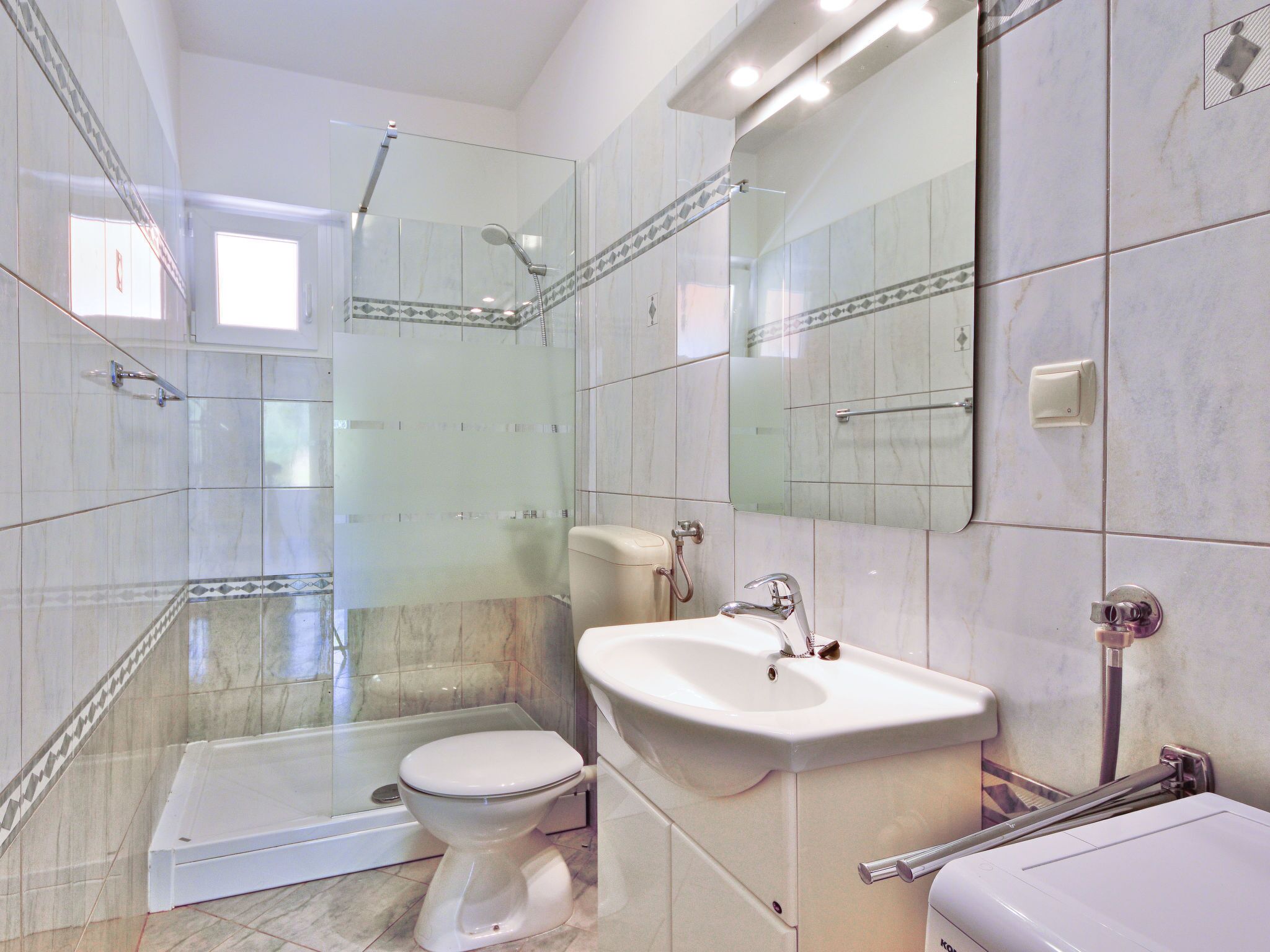 Une salle de bain avec une douche à parois de verre, des toilettes et un lavabo.