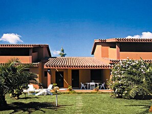 A hotel with a courtyard, palm trees, and a clear blue sky.