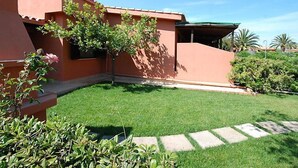 A building with a red exterior, a green lawn, and a stone pathway.