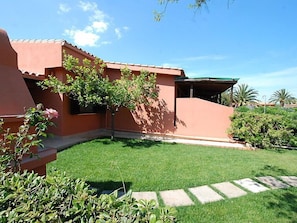 Stunning home with a flat roof and beautifully manicured lawn, featuring a patio area and lush plants.
