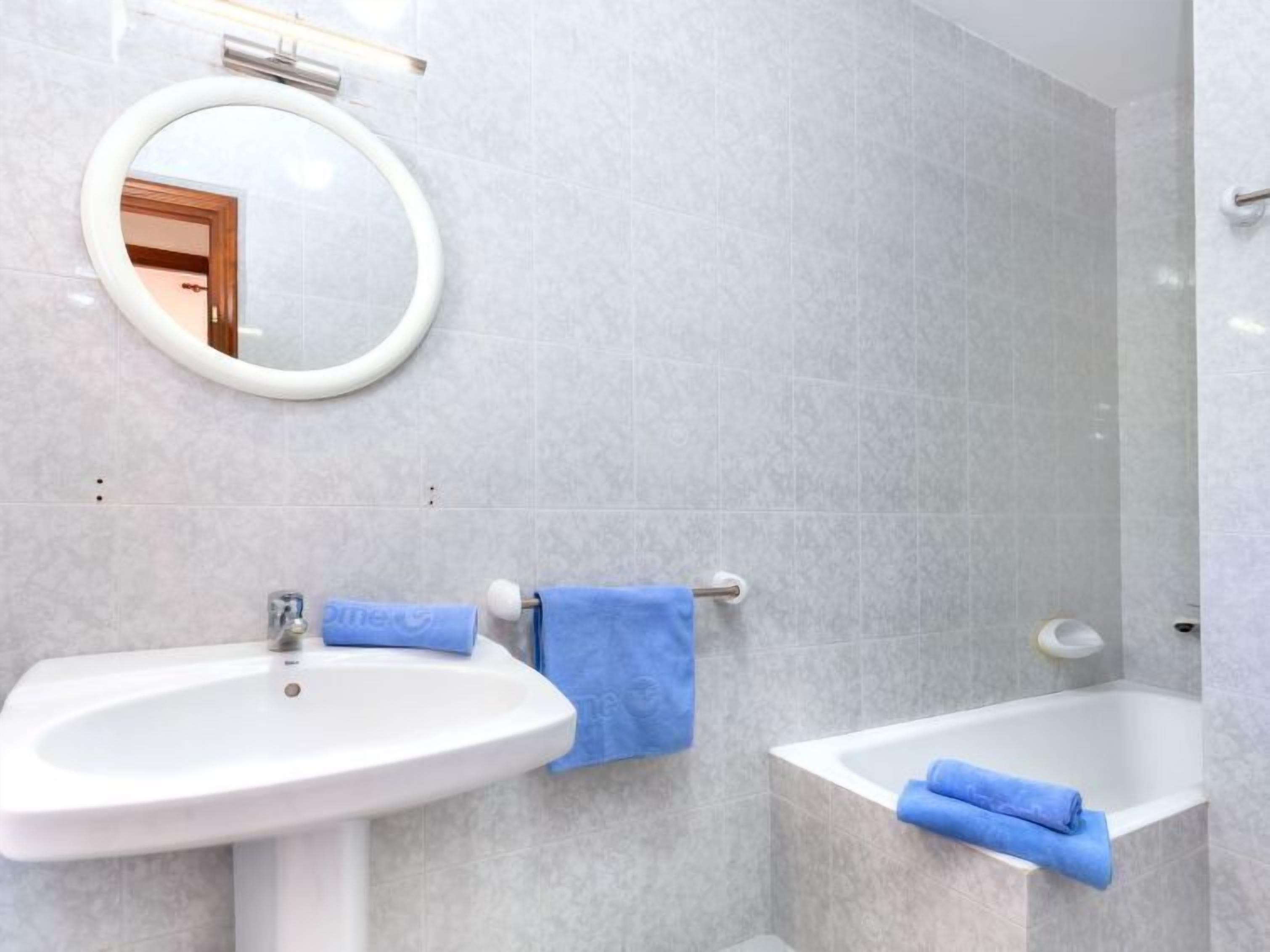 A bathroom with a sink, a mirror, and a bathtub.
