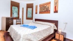 A bedroom with a bed, a dresser, a nightstand, and artwork on the walls.