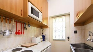 Una cuina compacta amb fogó, microones i rentatge.