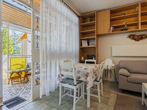 A cozy living area with a dining table, chairs, a sofa, and a bookshelf.