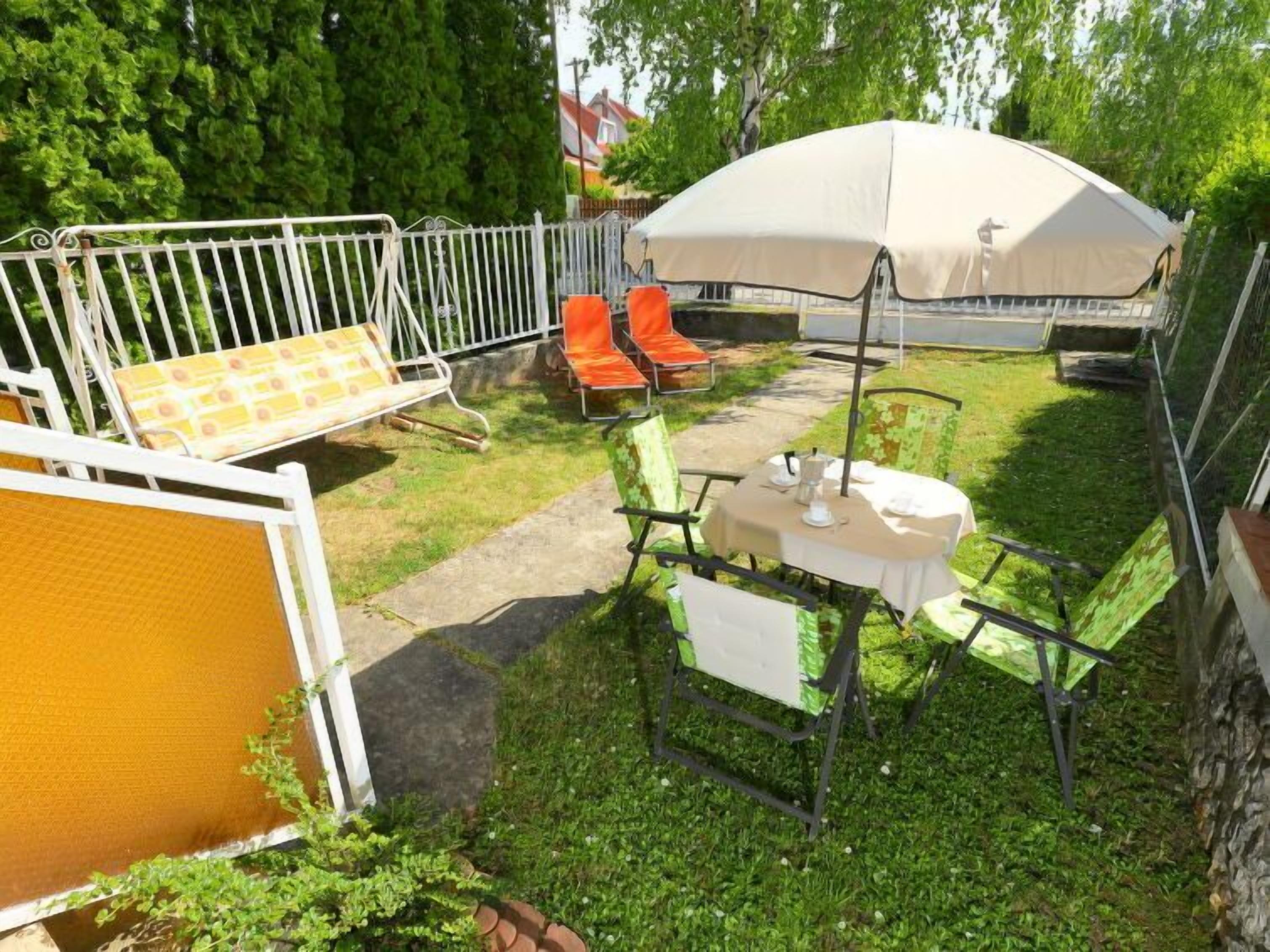 Un espace patio comprenant une table ronde et des chaises, un parasol et un coin salon avec des chaises et une table.