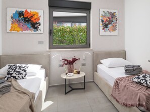 Un dormitorio moderno con dos camas, una mesita con un florero y cuadros abstractos en las paredes.