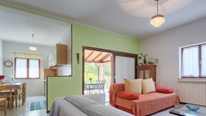 Une pièce confortable avec un lit, une petite table et un canapé. Il y a un coin cuisine avec une fenêtre et une table à manger.