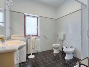 Une salle de bain équipée d  ’un lavabo, de toilettes, d’un bidet et d’une fenêtre avec un cadre rouge.