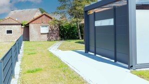 A modern building with a large glass facade, a brick structure with a tiled roof, and a pathway leading to the entrance. - Riedehuus by Interhome (Norddeich)