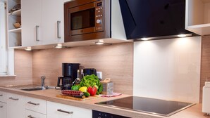 A modern kitchen with a microwave, stove, and dishwasher. There is a wooden countertop, a sink, and various kitchen appliances. - Riedehuus by Interhome (Norddeich)