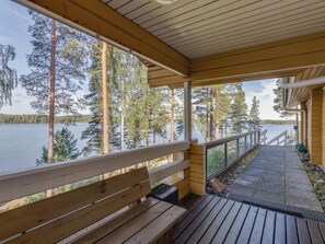 A wooden deck with a bench overlooking a lake, surrounded by trees.